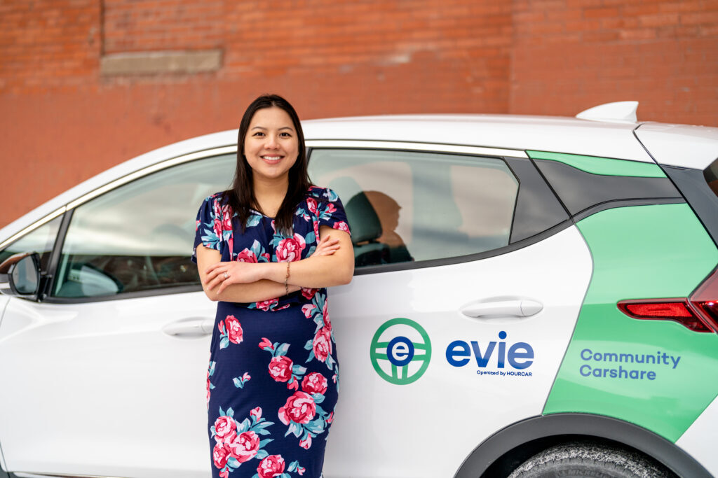 Person standing outside of a car with "Evie" on the side of it.